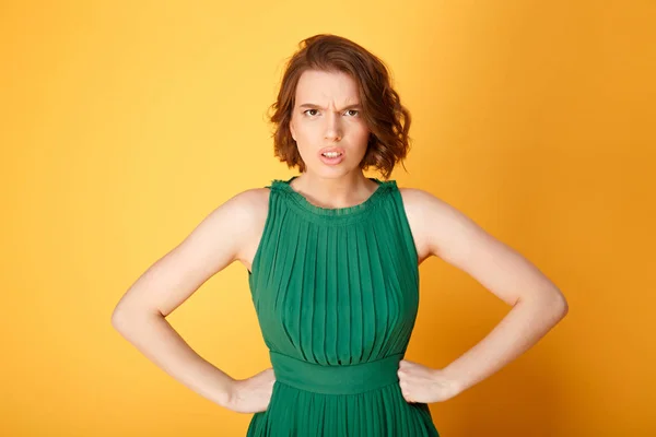 Portrait of unsatisfied woman akimbo isolated on orange — Stock Photo