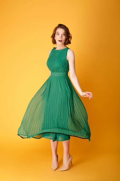 Jeune belle femme en robe verte isolé sur orange — Photo de stock