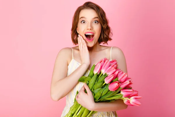 Femme surprise avec bouquet de tulipes printanières isolées sur rose — Photo de stock