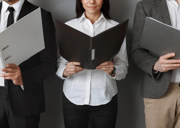 Partial view of business colleagues with folders against grey wall — Stock Photo