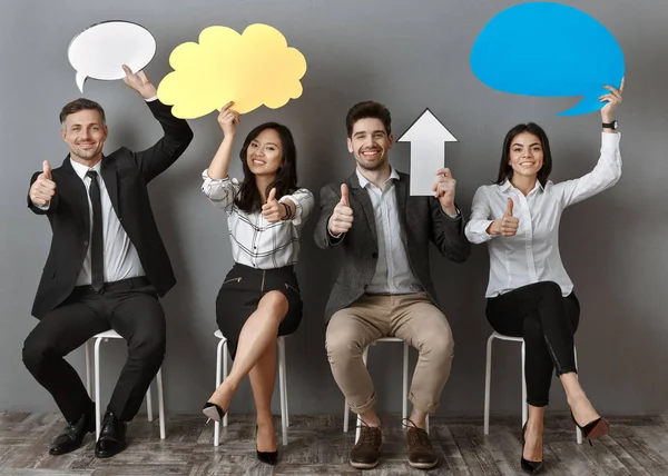 Multiethnic business people with paper chat bubbles and arrow showing thumbs up while waiting for job interview — Stock Photo