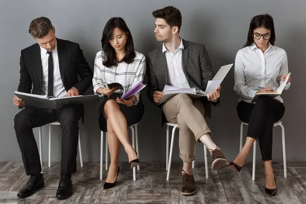 Personas de negocios multiculturales enfocadas con carpetas y cuadernos a la espera de entrevista de trabajo — Stock Photo