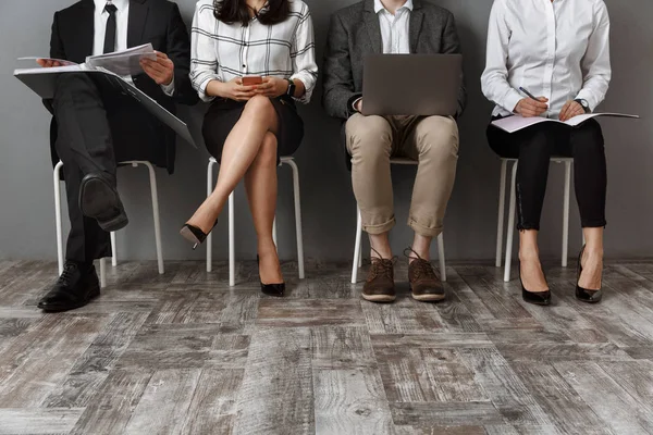 Vue partielle des gens d'affaires avec des appareils numériques et des dossiers en attente d'un entretien d'embauche — Photo de stock