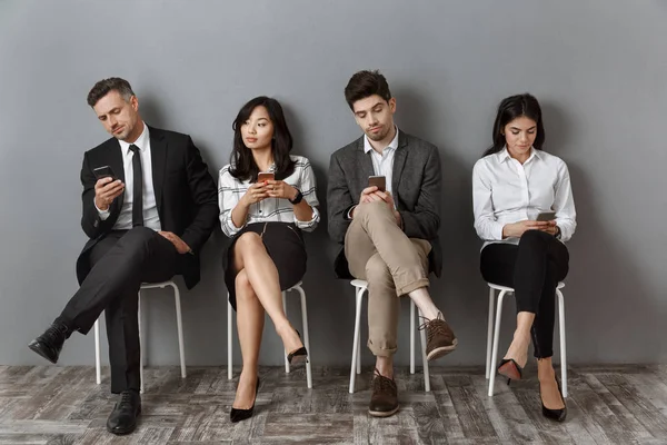 Interracial business people in formal wear with smartphones waiting for job interview — Stock Photo