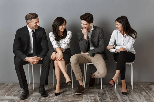 Gente de negocios interracial en ropa formal teniendo conversación mientras espera entrevista de trabajo - foto de stock