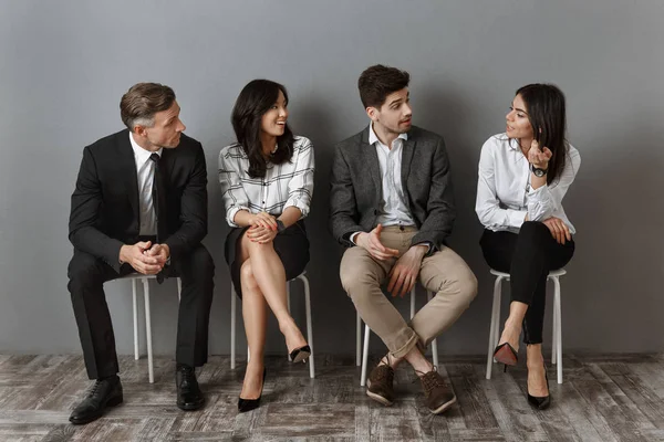 Interrassische Geschäftsleute in formeller Kleidung unterhalten sich miteinander, während sie auf ein Vorstellungsgespräch warten — Stockfoto