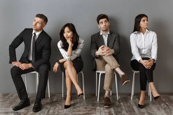 Gente de negocios interracial pensativa en ropa formal a la espera de entrevista de trabajo - foto de stock