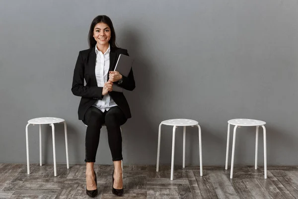 Sonriente mujer de negocios en traje con portátil a la espera de entrevista de trabajo - foto de stock
