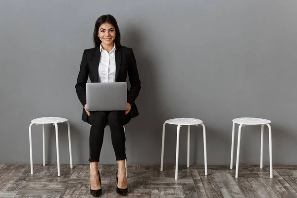 Smiling businesswoman in suit with laptop waiting for job interview — Stock Photo