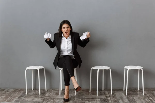 Mujer de negocios enojada en traje con papeles envueltos esperando entrevista de trabajo - foto de stock