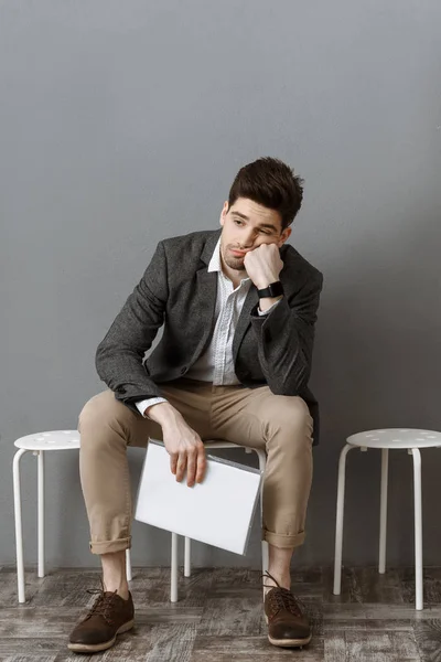 Pensativo hombre de negocios con documentos a la espera de entrevista de trabajo en silla - foto de stock