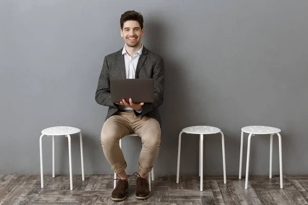 Sonriente hombre de negocios con portátil mirando a la cámara mientras espera la entrevista de trabajo - foto de stock