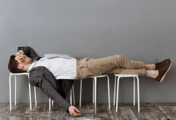 Tired businessman with documents sleeping on chairs wile waiting for job interview — Stock Photo