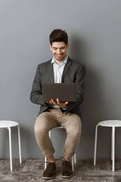 Sonriente hombre de negocios usando el ordenador portátil mientras espera la entrevista de trabajo - foto de stock