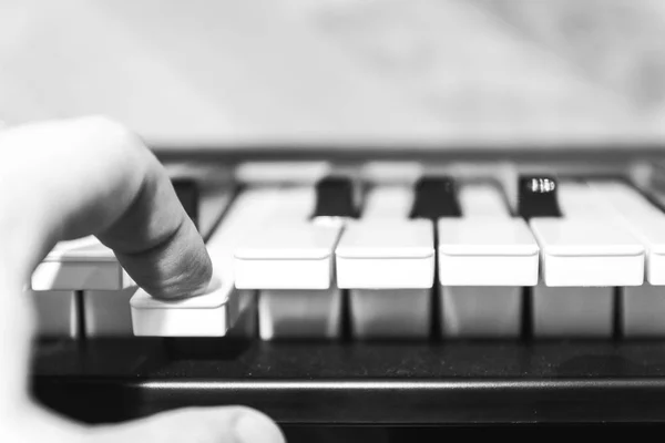 Los dedos humanos presionan la tecla del piano. Foto en blanco y negro . —  Fotos de Stock