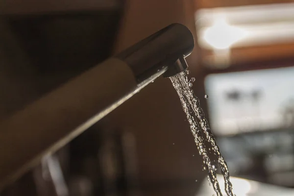 Een stroom van water uit de kraan stroomt in de ochtend op een wazig — Stockfoto