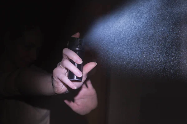 Žena je chráněn plynu pepřový sprej ve tmě, černý — Stock fotografie