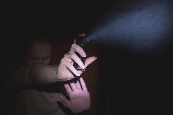 一个女人是在黑暗中的气体胡椒喷雾保护, 黑色 图库照片