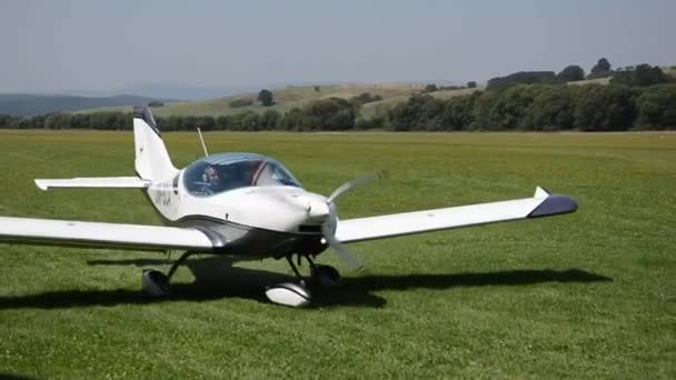 Branco duplo assento hélice-driven PS-28 Cruiser avião pára de se mover na faixa de aterragem grama em pequeno aeroporto — Vídeo de Stock