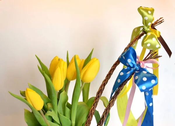 Spring composition: two easter whips with bunch of yellow tulips, empty background