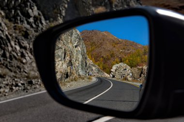 - Rusya. Altai Dağı. Maly Yaloman köyünün yakınındaki arabanın yan aynasında Chui yolunun yansıması.