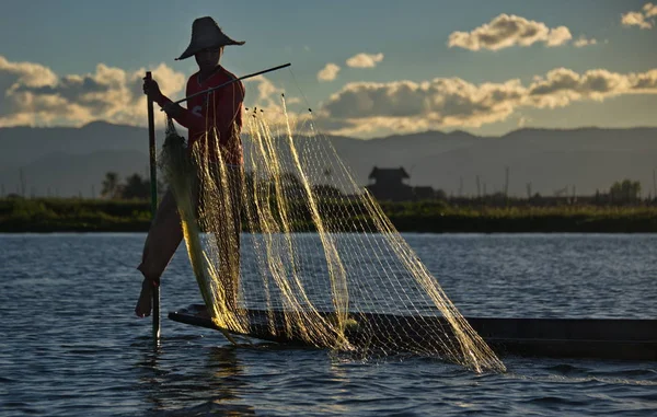缅甸曼德勒 2016年11月27日 在夕阳西下的背景下 英勒湖的渔夫把网整理好 站在船的边缘 一边控制着船 一边用脚拿着桨 — 图库照片