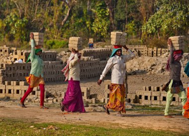 Assam. Hindistan. 8 Şubat 2016. Küçük bir tuğla fabrikası. Genç kızlar daha fazla ısınmak için kafalarında 8 adet kurumuş kil tuğla taşıyorlar. Her tuğlanın ağırlığı 3.5 kg..