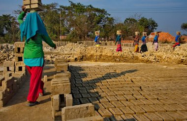 Assam. Hindistan. 8 Şubat 2016. Küçük bir tuğla fabrikası. Genç kızlar daha fazla ısınmak için kafalarında 8 adet kurumuş kil tuğla taşıyorlar. Her tuğlanın ağırlığı 3.5 kg..