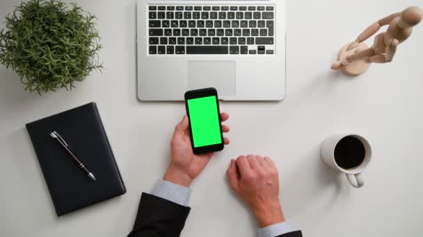 Ein Mann hält ein Telefon mit grünem Bildschirm in der Hand — Stockvideo