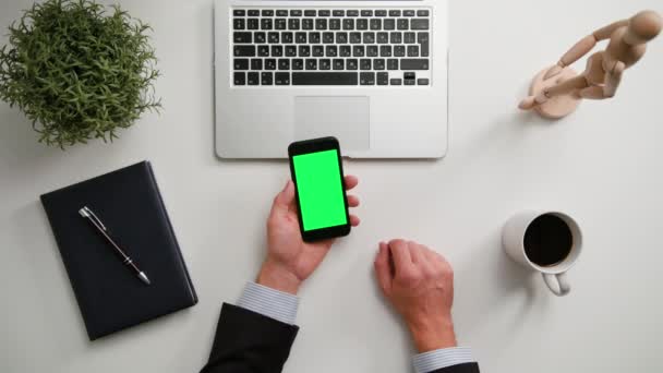 Ein Mann hält ein Telefon mit grünem Bildschirm in der Hand — Stockvideo