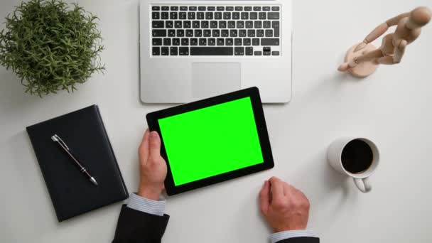 Manos de hombre sosteniendo un i-Pad con una pantalla verde — Vídeo de stock