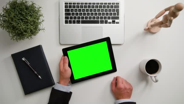 En Mans händer som håller en i-Pad med en grön skärm — Stockvideo