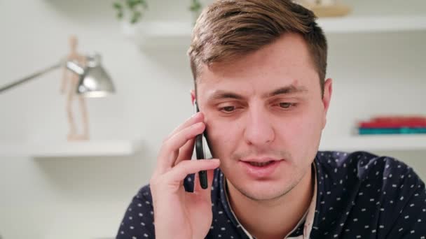 En ung mann som snakker i mobilen på kontoret – stockvideo