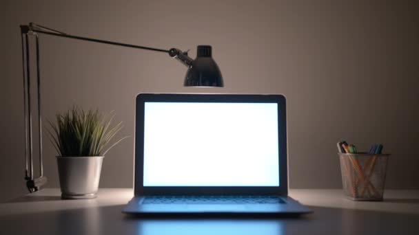 Gece masada beyaz bir ekran ile dizüstü bilgisayar — Stok video