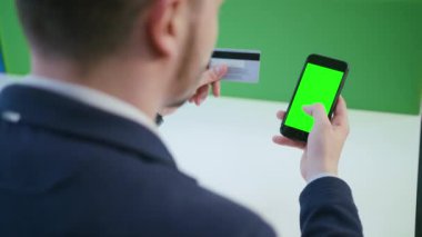 Bir akıllı telefon ile yeşil bir ekran kullanan bir genç adam