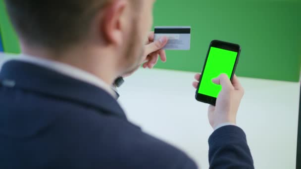 Un giovane utilizzando uno smartphone con uno schermo verde — Video Stock