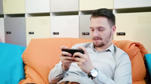 Muž hraní her na smartphonu uvnitř — Stock video