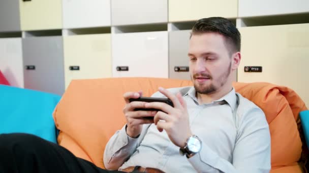 Man spelen van spelletjes op de Smartphone binnenshuis — Stockvideo