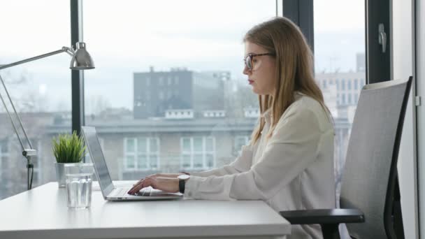 Bisinesswoman sitzt und benutzt einen Laptop drinnen — Stockvideo