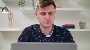 Genç bir adam kapalı bir bilgisayar kullanarak