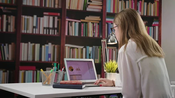 Joven dama usando un ordenador portátil en la biblioteca — Foto de Stock