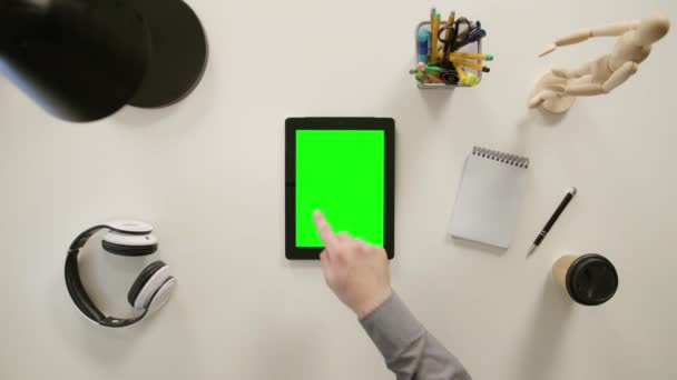 Un doigt touchant un écran vert de l'iPad 