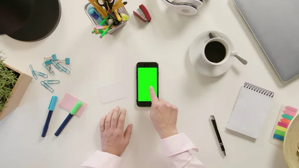Пальцем, торкаючись смартфон з зеленим екраном — стокове фото