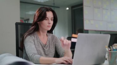 Bir dizüstü bilgisayarda çalışma ofisinde oturan bir Bayan