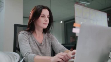 Bir dizüstü bilgisayarda çalışma ofisinde oturan bir Bayan