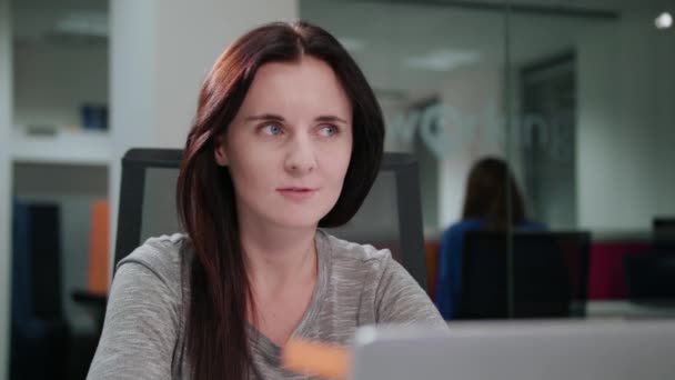 Uma senhora sentada no escritório na frente de um laptop — Vídeo de Stock