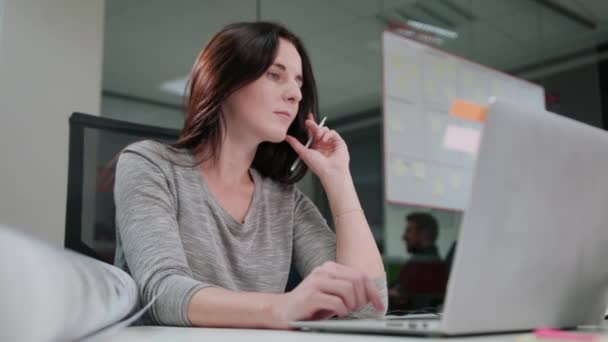 Eine Dame sitzt im Büro und arbeitet an einem Laptop — Stockvideo