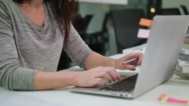 Eine Dame sitzt im Büro und tippt auf einem Laptop — Stockvideo