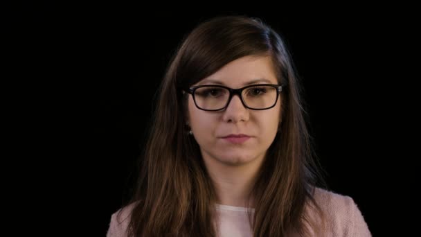 Una joven con gafas mira asombrada — Vídeo de stock