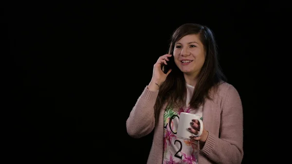 Eine glückliche Dame mit Telefon vor schwarzem Hintergrund — Stockfoto